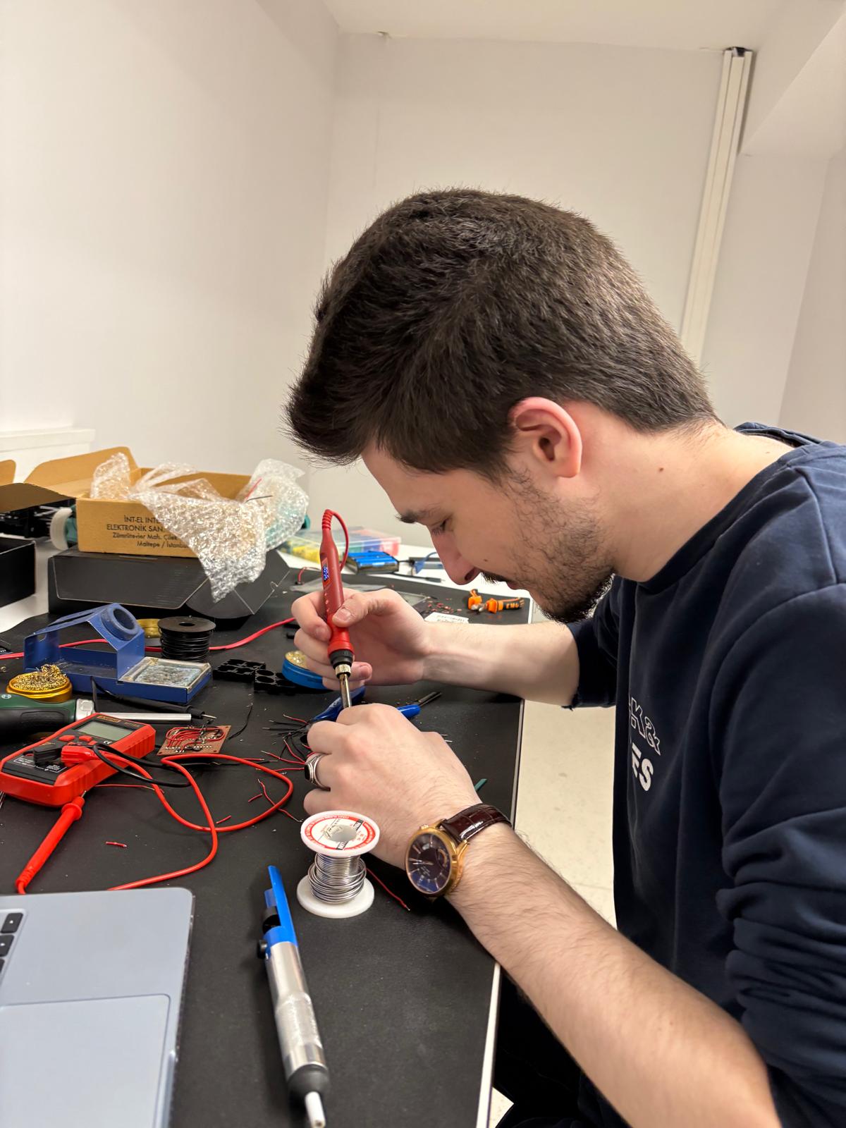 Batuhan Gümüş soldering a circuit board at his workbench